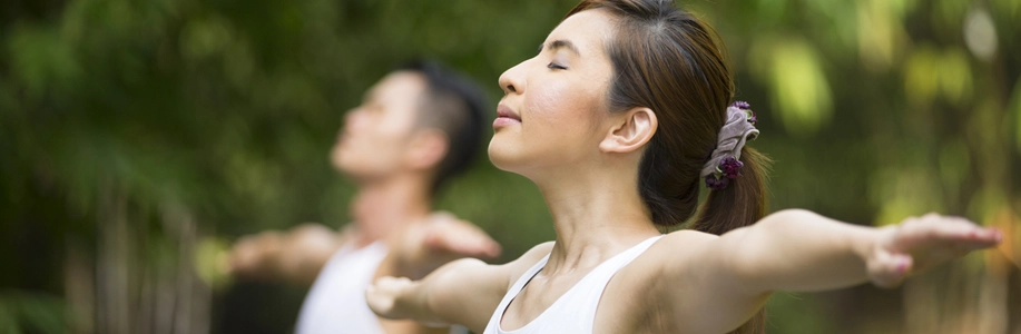 Woman spreads arms and takes deep breath with eyes closed