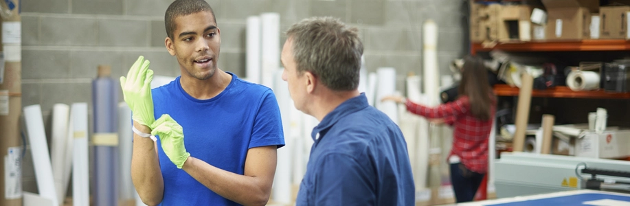 Man puts on work glove while speaking to manager