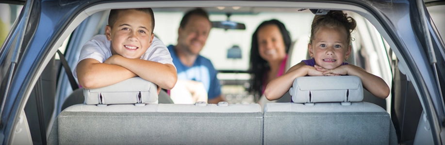 Family of four looks out the back of vehicle with smiles