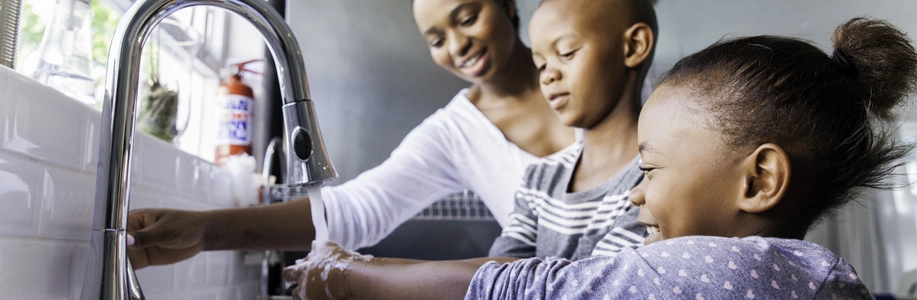 Mom helps kids wash hands in kitchen sink